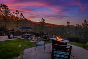 un patio con mesa, sillas y hoguera en Sierra Vista Lookout Lodge with Creek, Waterfall and Waterholes, minutes from Bass Lake and Yosemite South Gate, en North Fork
