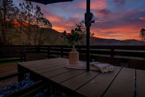a wooden table with a vase of flowers on top of a deck at Sierra Vista Lookout Lodge with Creek, Waterfall and Waterholes, minutes from Bass Lake and Yosemite South Gate in North Fork