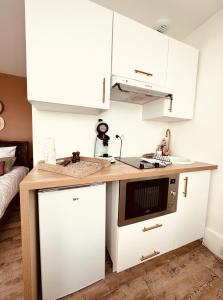 uma pequena cozinha com armários brancos e um lavatório em Studio 1 du SPA Célinie em Warcq