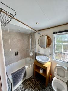 a bathroom with a tub and a sink and a toilet at Leaf Lane Lodge in Newton on the Moor