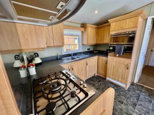 a kitchen with wooden cabinets and a stove top oven at Leaf Lane Lodge in Newton on the Moor