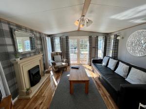 a living room with a black couch and a fireplace at Leaf Lane Lodge in Newton on the Moor
