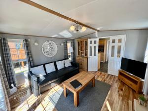 a living room with a black couch and a table at Leaf Lane Lodge in Newton on the Moor +10 photos