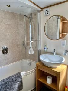 a bathroom with a sink and a tub and a mirror at Leaf Lane Lodge in Newton on the Moor