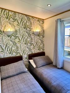 a bedroom with two beds and a wall with a wallpaper at Leaf Lane Lodge in Newton on the Moor