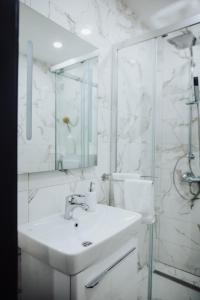 a white bathroom with a sink and a mirror at Modern Apartment 3 in Brčko