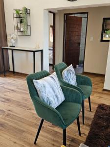 a green chair with two pillows in a living room at Pine View Guesthouse Graskop in Graskop