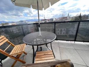 una mesa y sillas en un balcón con sombrilla en City center apartment with nice balcony, en Žilina