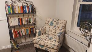 a chair next to a book shelf with books at Waters Edge, Town house in Stourport-on-Severn in Stourport