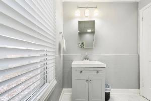 uma casa de banho branca com um lavatório e um espelho em Beauty Sleep on Bellevue 