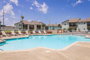 une grande piscine avec des chaises longues dans un complexe dans l'établissement AH-E117 Remodeled First Floor Condo, Across From The Shared Pool & Hot Tub, Near Marina & Ferry, à Port Aransas