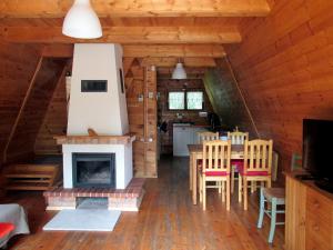 a dining room and kitchen in a log cabin with a fireplace at Jeżówka in Sasino