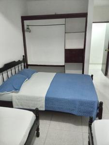 um quarto com uma cama com lençóis azuis e brancos em Hotel Rosandy Galaxy em Cartagena das Índias