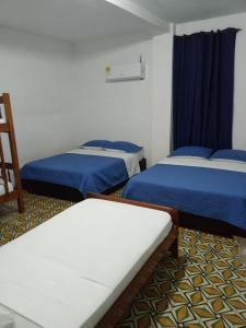 a room with three beds and a blue curtain at Hotel Rosandy Galaxy in Cartagena de Indias