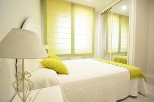 a white bedroom with a bed and a lamp at Apartamento en pleno centro de Portonovo, Sanxenxo in Sanxenxo