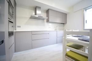 una cocina blanca con armarios blancos y fregadero en Apartamento en pleno centro de Portonovo, Sanxenxo, en Sanxenxo