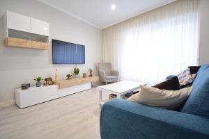 a living room with a blue couch and a tv at Apartamento en pleno centro de Portonovo, Sanxenxo in Sanxenxo