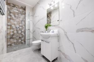 a white bathroom with a toilet sink and a shower at Polanka Apartamenty in Niechorze