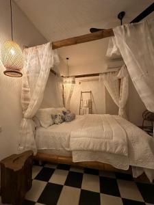 a bedroom with a canopy bed with curtains and a checkered floor at Casa Teresa Hotel in Cartagena de Indias