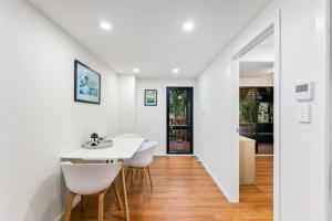 un comedor blanco con una mesa y sillas blancas en A 1BR slice of Titirangi Heaven - WiFi - Netflix en Auckland