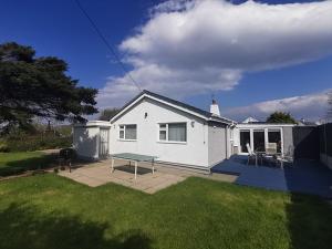 a white house with a picnic table in a yard at Gilfach-3 Bed-Dog Friendly-Detached Bungalow in Trearddur
