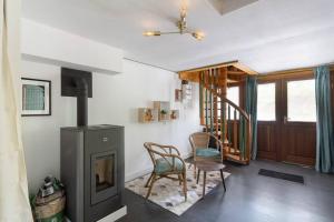 a living room with a fireplace and a chair at Agréable chalet cocooning en lisière de forêt in Champdray