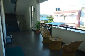 balcón con sillas y vistas a un edificio en THE SURRYA MAX RESIDENCY, en Pollachi