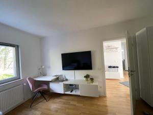 Habitación blanca con escritorio y TV en la pared. en KickEns, en Adenau