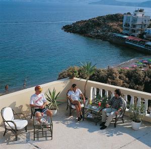 a group of men sitting on a balcony overlooking the water at Mare Hotel Apartments in Agios Nikolaos