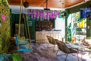 un patio con sillas, mesas y flores púrpuras en Encanto Del Mar Hotel en Jacó