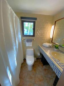 a bathroom with a toilet and a sink and a window at KASA Rio Mar Villa for 2 in Rio Grande