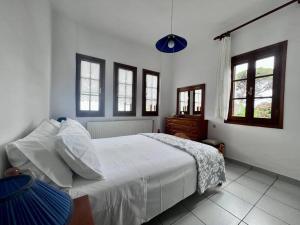 a bedroom with a bed with white sheets and windows at Sea & Mountain Pelion in Mouresi
