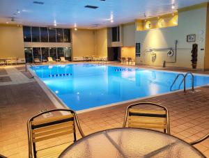 a large blue swimming pool with chairs and tables at La Quinta by Wyndham Appleton College Avenue in Appleton