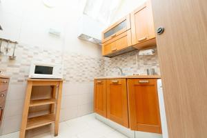 uma pequena cozinha com armários de madeira e um micro-ondas em Appartamento Napoli nel cuore di Bari em Bari