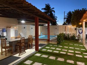 un patio trasero con mesa, sillas y piscina en Chácara Paraíso do Rio em Aracaju, en Aracaju