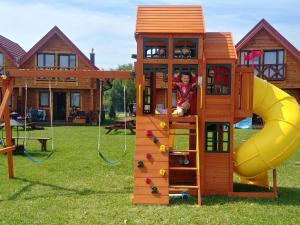 a child is climbing up a wooden play house at Semi-detached house, Niechorze in Niechorze