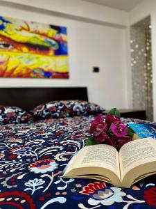 an open book on a bed with flowers on it at Alpha22 Apartment in Giardini Naxos