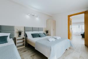 a white bedroom with two beds with towels on them at Willa Karol in Karwia