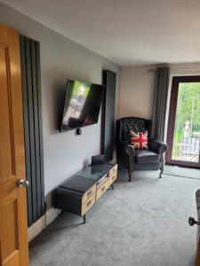 a living room with a chair and a tv on the wall at Luxury Penthouse on Waterside Knaresborough in Knaresborough