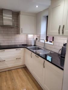 a kitchen with white cabinets and a sink at Luxury Penthouse on Waterside Knaresborough in Knaresborough