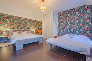 2 camas en un dormitorio con papel pintado con motivos florales en LA CLER'HIER, en Clérey