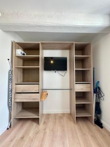 Habitación con armario con estanterías de madera y TV. en Charmant T2 Cosy en plein centre ville, en Montluel