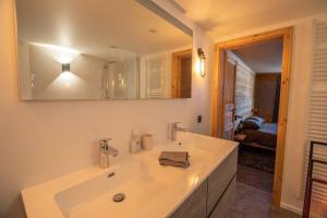 a white bathroom with a sink and a mirror at Pétillant Chalet aux 3 étangs avec SPA, Sauna et Véranda in Gerbépal