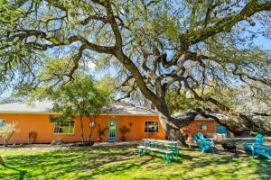 een oranje huis met blauwe picknicktafels onder een boom bij The Heyday Hacienda in Sunset Valley, Pet-Friendly, Pool, Fire Bowl, Smart TVs in Austin