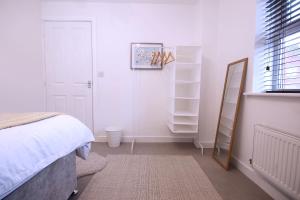 a white bedroom with a bed and a mirror at Double bed with Parking Desk TV Wi-Fi in Modern Townhouse in Long Eaton in Long Eaton