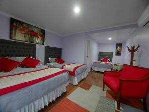 a bedroom with three beds and a red chair at Hotel Rarinco in Los Ángeles