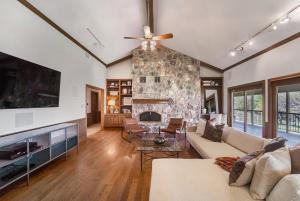 sala de estar con chimenea de piedra y ventilador de techo en Tarcoola Riverfront Ranch, Billiards and Smart TVs en Bastrop