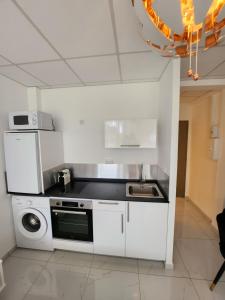 uma cozinha branca com um lavatório e um fogão em HELLO GUYANE, Marina 1, Studio Prestige 5 étoiles em Saint-Laurent du Maroni