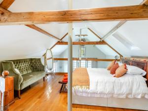 an attic bedroom with a bed and a couch at The Old Parish Hall in Quendon
