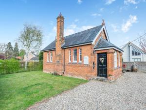 a brick house with a chimney on top of a yard at The Old Parish Hall in Quendon